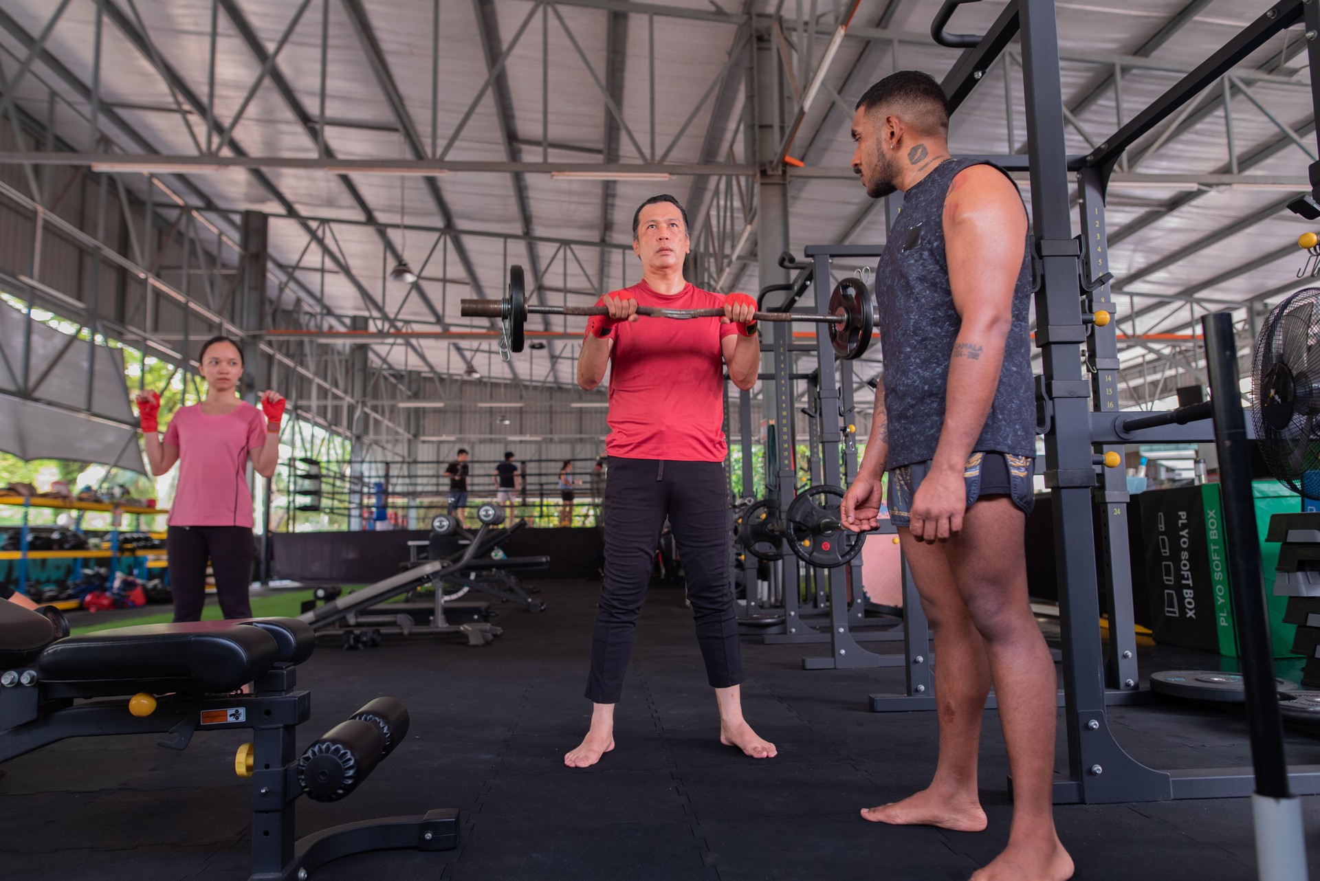 Asian Fitness instructor teaching students correct method to lifting weight equipment at gym stock photo