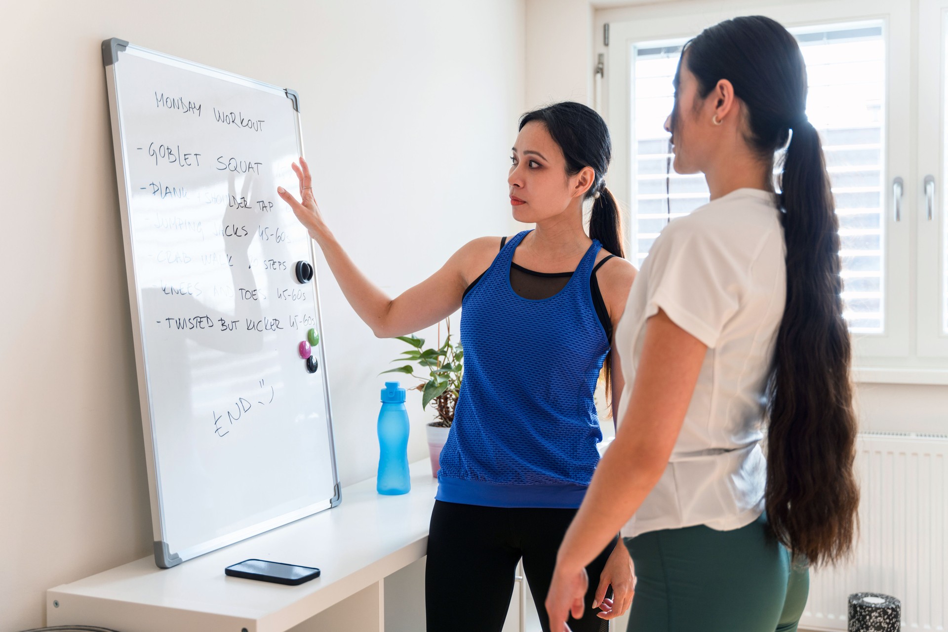 Two Asian Sportswomen  Discussing Exercise Plan For Home Workout